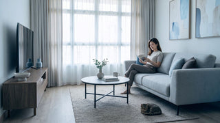 Modern contemporary HDB living room with grey sofa, wood TV console, round coffee table, and neutral decor
