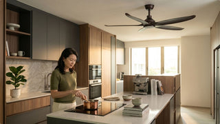 Modern Singapore kitchen with dark ceiling fan above island and woman cooking in warm natural light