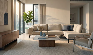 Modern Singapore condo living room with beige sectional sofa, wood TV console, coffee table, and large windows showing a practical standing aircon setup.
