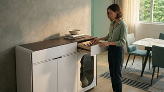 Woman opening a drawer in a narrow sideboard cabinet in a modern dining area