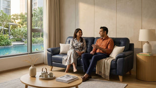 Couple sitting on a navy blue leather sofa in a warm Singapore living room with pool view and wooden coffee table