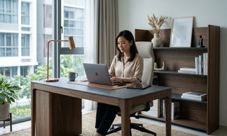Woman working at a wooden office desk with shelves in a bright Singapore home office.