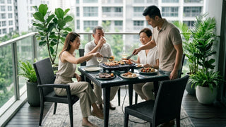 Family sharing food from an outdoor electric BBQ grill at a balcony dining table in Singapore
