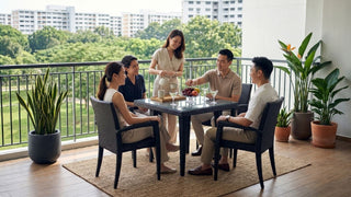 Friends enjoying drinks around outdoor rattan chairs and glass table on a spacious Singapore balcony