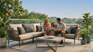 relaxing on a beige outdoor sectional sofa on a tropical Singapore balcony with glass railing and garden view