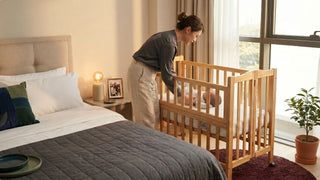 Parent checking baby in a wooden cot beside a bed in a warm Singapore bedroom