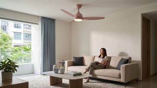 Pink ceiling fan above a beige sofa in a bright Singapore living room with a coffee table, curtains, and indoor plant.