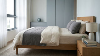 Pocket spring mattress on a wooden bed frame in a calm Singapore bedroom with soft neutral bedding.