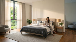 Woman reading on a queen bed frame in a spacious landed home bedroom with bedside tables, curtains, and open walking clearance.