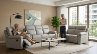 Senior woman relaxing on a recliner sofa with footrest while a man stands nearby in a bright condo living room