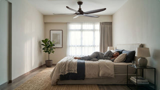 Woman resting under a recommended ceiling fan in a cosy modern Singapore bedroom