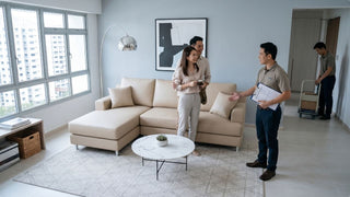 Couple reviewing furniture setup with staff in a renovated HDB living room with beige sectional sofa