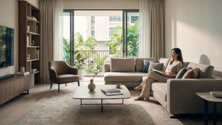 Woman reading in a renovated Singapore living room with sofa, coffee table, TV console, and balcony view.