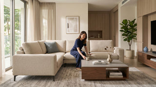 Modern Singapore living room with beige sectional sofa, coffee table, TV console, indoor plant, and warm wood built-ins after renovation.