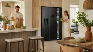 Modern Samsung refrigerator in a bright Singapore kitchen with a couple unpacking groceries in a warm HDB-style home
