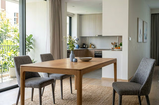 Scandi wood dining table with grey upholstered chairs in a bright open-plan Singapore home