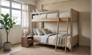 Wooden bunk bed in a compact HDB bedroom with neutral bedding, bedside table, indoor plant, and daylight from the window.