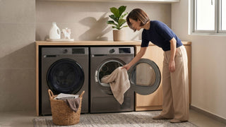 Woman loading laundry into a separate dryer beside a washing machine in a compact Singapore laundry space