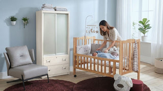 Cosy Singapore baby nursery with wooden cot, dresser, wardrobe, feeding chair, and soft natural light