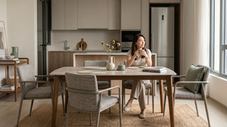 Woman sitting at a dining table in a Singapore apartment with a refrigerator placed in a built-in kitchen alcove