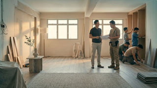 Contractors installing flooring and carpentry during a Singapore house renovation with plans on site