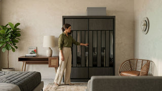 Woman checking a sliding door wardrobe in a calm bedroom with neutral furniture