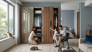 Family using a wooden sliding-door wardrobe with mirror panels in a compact Singapore studio apartment bedroom.