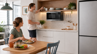 Small wall-mounted microwave in a bright modern Singapore kitchen with a compact dining area and everyday family meal setup.