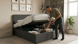 Man organising clothes inside a grey smart bed frame with gas lift storage in a compact Singapore bedroom