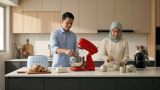 Couple using SMEG kitchen appliances on a modern Singapore kitchen island with toaster, kettle, and stand mixer