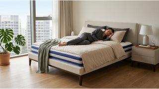 Person resting on a Solano mattress in a bright Singapore bedroom with soft bedding and city view