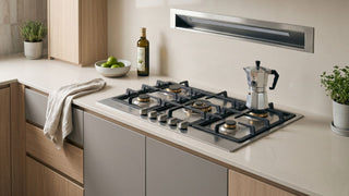 Stainless steel gas cooker with multiple burners in a modern Singapore kitchen with a slim wall-mounted range hood.