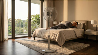 Stand fan placed near a bed in a bright Singapore bedroom with balcony and warm daylight
