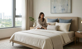 Woman arranging standard pillows on a queen bed in a bright Singapore bedroom