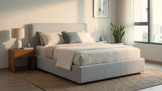Fabric storage bed in a bright Singapore bedroom with neutral bedding, wooden bedside table, and soft natural light.