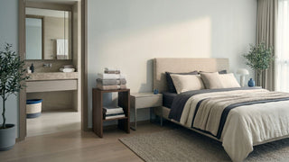Stack of folded towels on a bedside storage table beside a neutral bedroom and connected bathroom in a Singapore home.