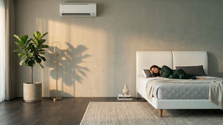 Wall-mounted aircon cooling a modern Singapore bedroom with white bed and warm wood furniture
