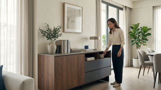 Woman opening a walnut storage unit with drawers and shelves in a bright Singapore living room