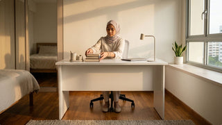 Woman organising books at a white bedroom study table with chair and window-side natural light