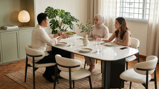 Friends dining at a white oval table with black pedestal base and curved white chairs in a cosy Singapore home