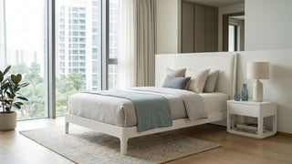 White single bed frame in a bright Singapore condo bedroom with soft neutral bedding, bedside table, rug, and city view.