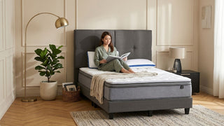 Woman reading on a white single mattress in a cosy modern bedroom with neutral decor