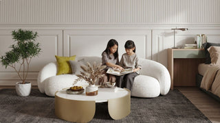 Two girls reading on a cosy white sofa beside a bed, showing a practical study-sleep room layout for children