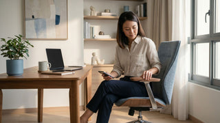 Woman checking an office chair armrest while using her phone in a Singapore home office setup.