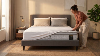 Woman making a bed with a Derucci mattress in a cosy Singapore bedroom with warm wood flooring