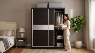 Woman organising clothes in a dark wood wardrobe with sliding doors