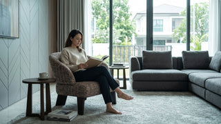 Woman reading on a brown 1 seater sofa in a modern Singapore living room