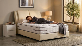 Woman sleeping on a Slumberland mattress in a cosy Singapore bedroom with warm lighting