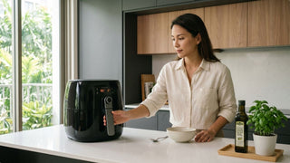Woman using a black air fryer on a kitchen island in a bright modern home