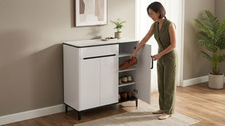 Woman placing shoes inside a white plastic shoe cabinet at home